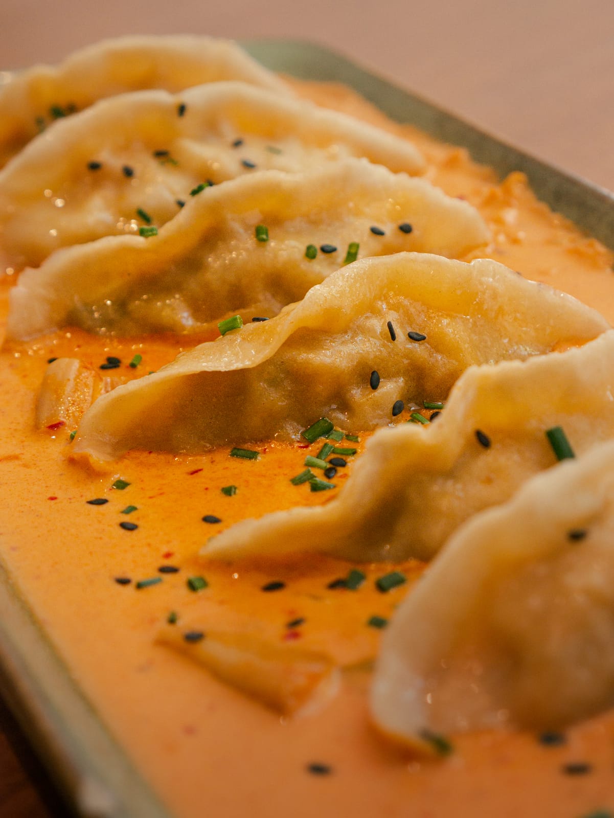 Korean dumplings in spicy sauce with chives and black sesame
