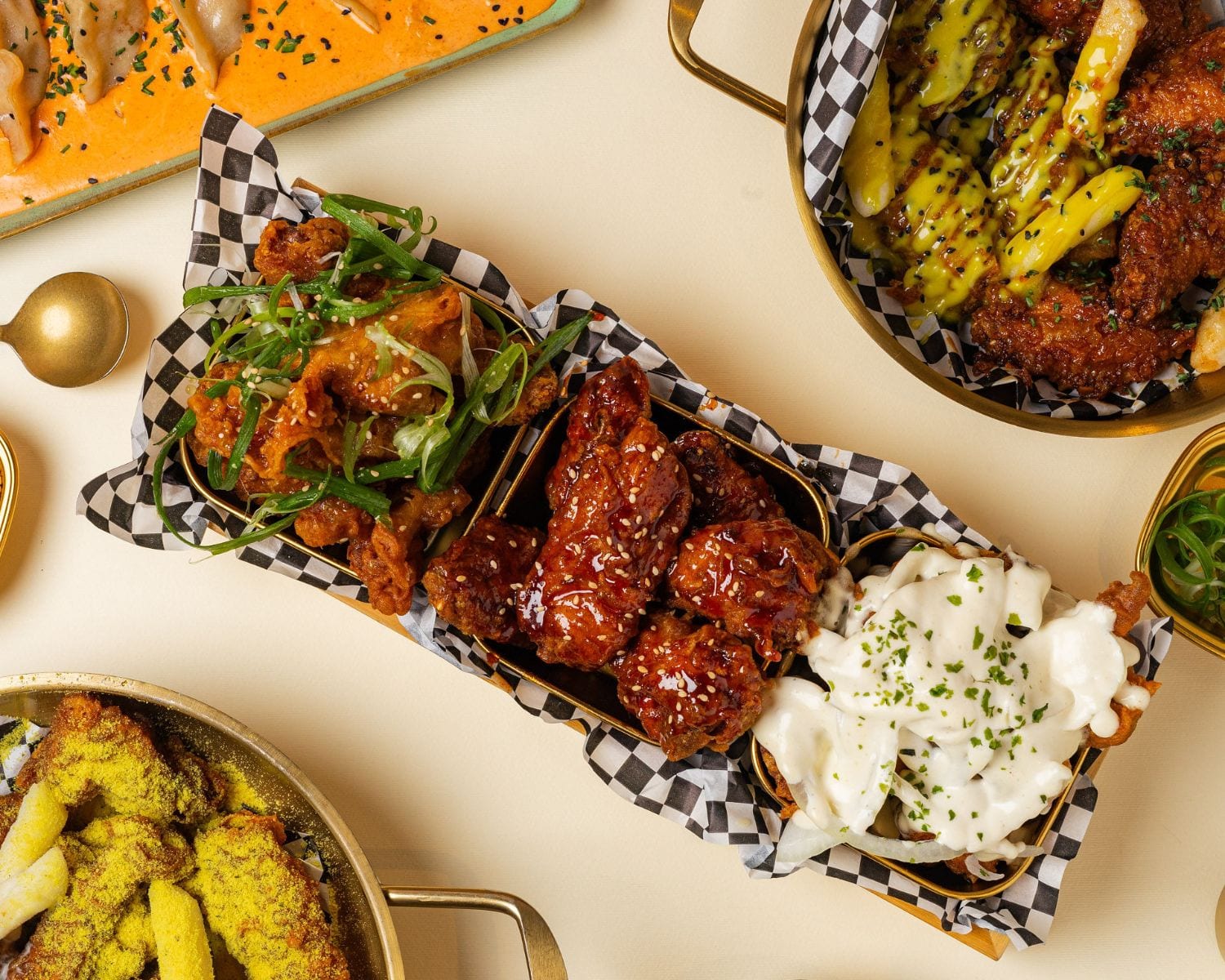 Tray of Korean fried chicken with different sauces, surrounded by other dishes on the table