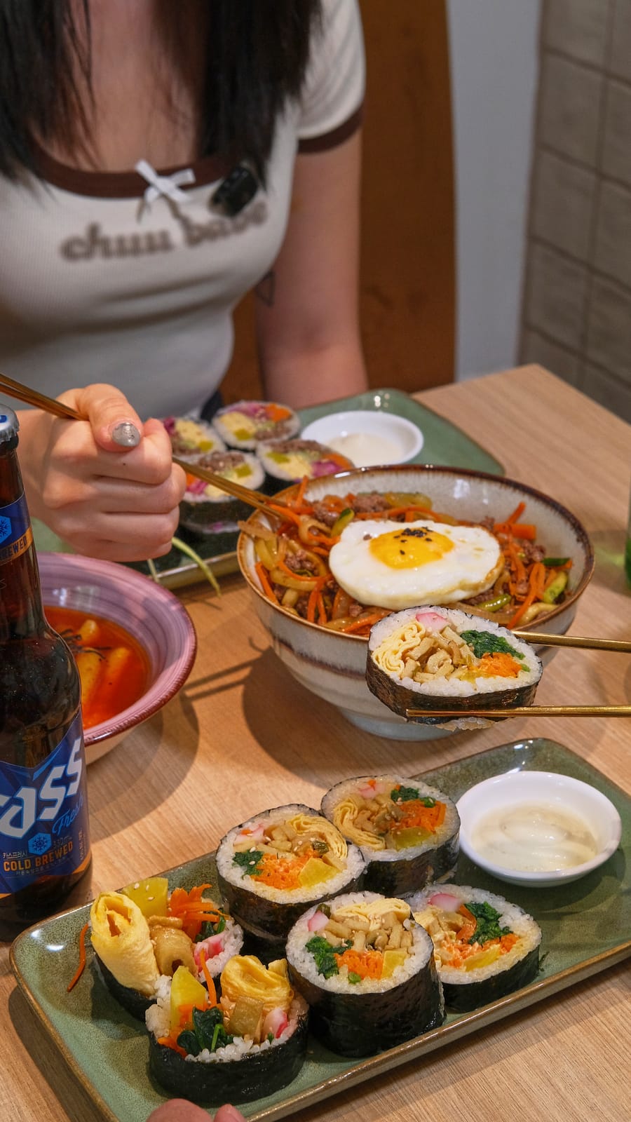 Bulgogi dosirak with fried egg and kimbap, with a Cass beer on the table